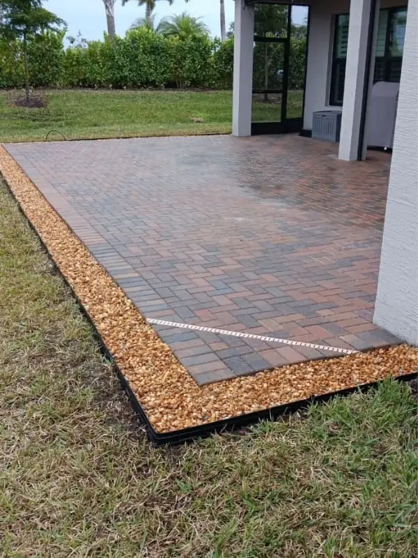Finished paver patio with decorative stone edging beside a home